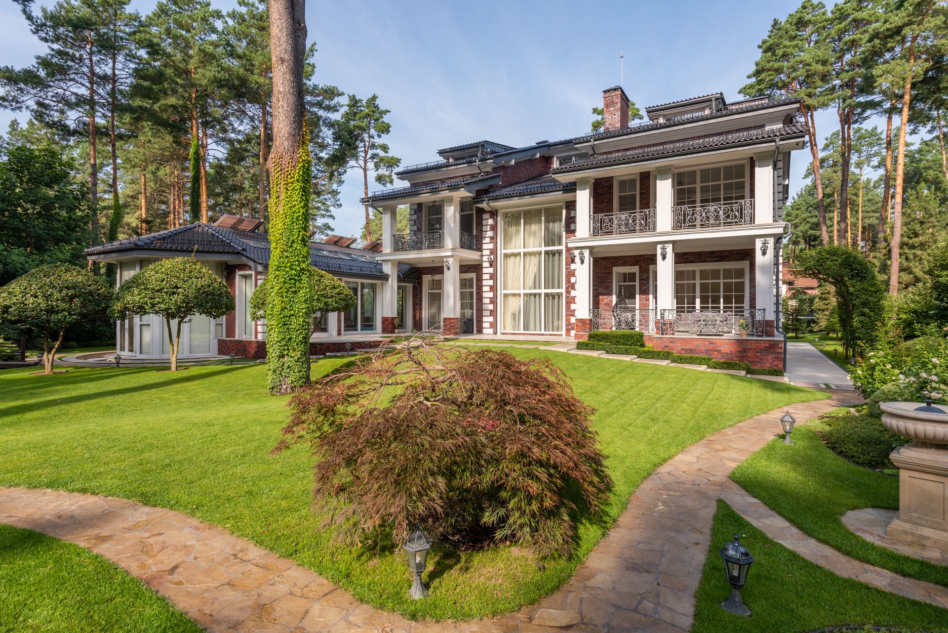 A green lawn, shaped planting beds, and stone paths around a home