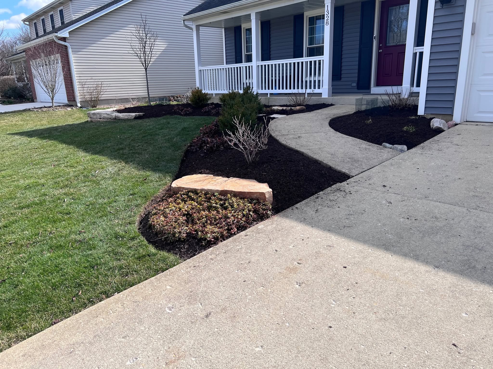 Company photo of fresh mulch and curved planting beds along a home’s front walkway